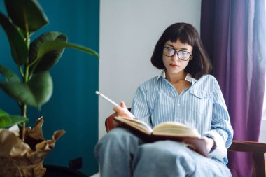 Evde genç bir kadın defter yazıp onunla çalışıyor. Serbest çalışan ve evde karantinada çalışırken notlar alan biri. Sosyal uzaklık. Kişisel İzolasyon