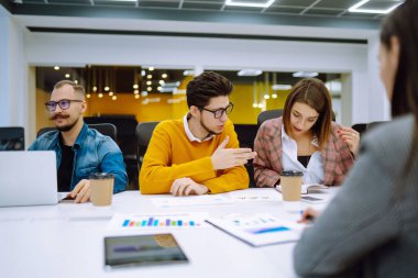İş arkadaşları yaratıcı ofiste birlikte çalışıyorlar. Gençler finansal sonuç değerlendirmesini tartışıyor evrak işleri fikir paylaşıyor, beyin fırtınası takım çalışmasında işbirliği yapıyor. Planlama, analiz.