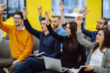 Bir konferansta birlikte oturan bir grup genç görüşlerini ifade etmek için ellerini kaldırdı. İş gurubu toplantısı seminer eğitim konsepti. Takım çalışmasında planlama, analiz, işbirliği.