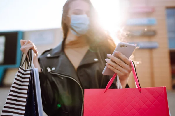 Mosolygó Védő Orvosi Maszkban Bevásárlószatyrokkal Telefonján Fiatal Vásárlás Után Város — Stock Fotó