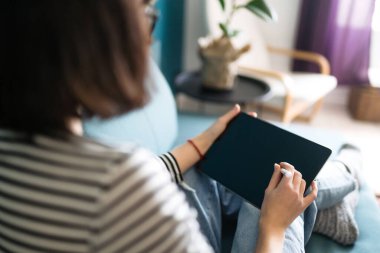 Tablet kullanan genç bir kadın, boş zamanlarını sosyal ağda sohbet ederek geçiriyor, serbest çalışan biri. Karantina karantinasında evden çalışıyor. Eğitim çevrimiçi.