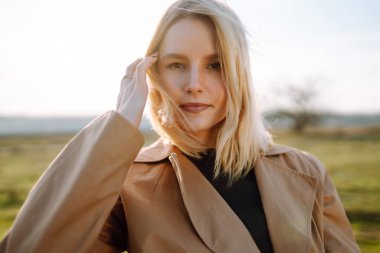 Genç bir kadının portresi çayırda duruyor, açık havada güneşli bir bahar gününün tadını çıkarıyor. İnsanlar, yaşam tarzı, seyahat, doğa ve tatil kavramı.