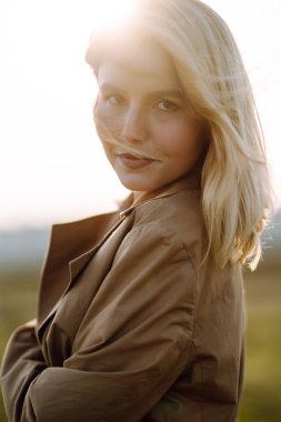 Genç bir kadının portresi çayırda duruyor, açık havada güneşli bir bahar gününün tadını çıkarıyor. İnsanlar, yaşam tarzı, seyahat, doğa ve tatil kavramı.