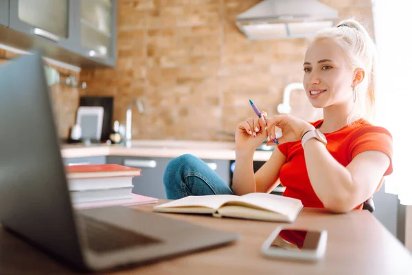 Young freelancer woman works and makes notes while working at home in quarantine lockdown. Social distancing. Self Isolation. Smiling woman working online or studying and learning while using notebook