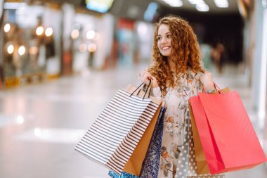 Modern alışveriş merkezinde çok renkli çantaları olan şık bir kadın. Tüketim sevinci. Tüketim, satış, alım, alışveriş, yaşam tarzı konsepti.
