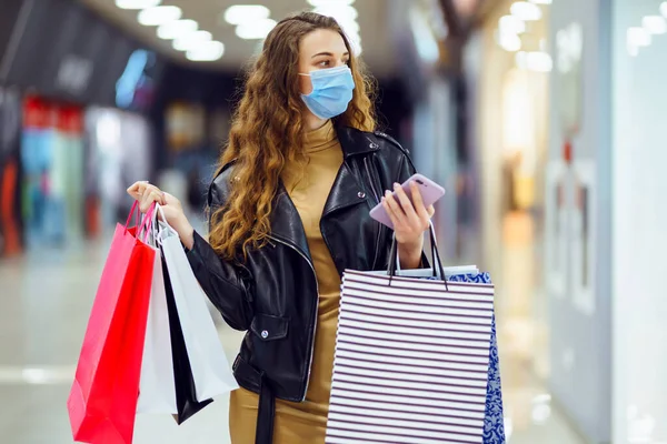 Mujer Joven Máscara Médica Protectora Con Bolsas Compras Usando Teléfono — Foto de Stock