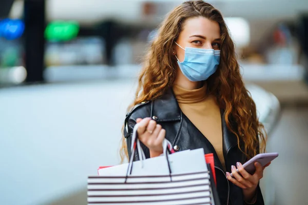 Young Woman Protective Medical Mask Shopping Bags Using Her Phone — Stock Photo, Image