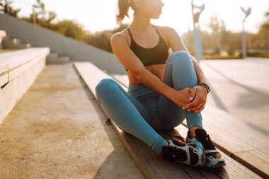 Spor kıyafetli genç bir kadın sabahları dışarıda egzersiz yapıyor. Yoğun bir antrenmandan önce kaslarını ısıtıyorum. Spor, aktif yaşam, spor eğitimi, sağlıklı yaşam tarzı..