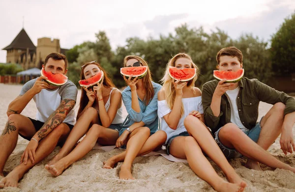 ビーチでリラックスしてスイカを食べる若い友人 人々のグループは一緒に夏のパーティーをお楽しみください ライフスタイル 休暇の概念 — ストック写真