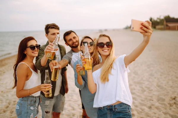 Group of people doing selfie with phone at the beach. Young friends enjoy summer party together. People, lifestyle, travel, nature and vacations concept.
