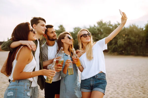 Group of people doing selfie with phone at the beach. Young friends enjoy summer party together. People, lifestyle, travel, nature and vacations concept.