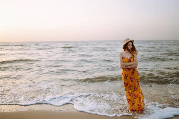 穿着漂亮衣服 头戴漂亮帽子的年轻女子站在海滩上 夕阳西下 放松和生活方式概念 — 图库照片