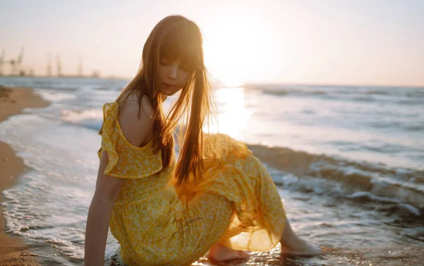 Genç bir kadın sahilde günbatımının tadını çıkarıyor. Kadınsı, çekici ve şehvetli bir siluet. Seyahat, hafta sonu, rahatlama ve yaşam tarzı konsepti.