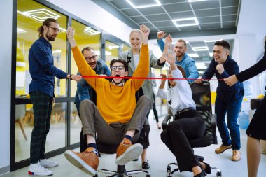 Genç iş arkadaşları birlikte eğleniyor, koltuklarda oturuyorlar, çeşitli heyecanlı ofis çalışanları tatilin tadını çıkarıyorlar, gülüyorlar, eğlenceli aktiviteler yapıyorlar, kurumsal başarıyı kutluyorlar..