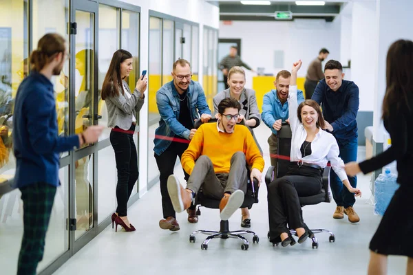 Genç iş arkadaşları birlikte eğleniyor, koltuklarda oturuyorlar, çeşitli heyecanlı ofis çalışanları tatilin tadını çıkarıyorlar, gülüyorlar, eğlenceli aktiviteler yapıyorlar, kurumsal başarıyı kutluyorlar..