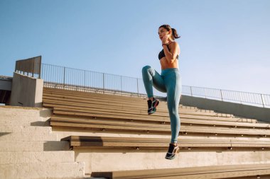 Spor kıyafetli genç bir kadın yoga yapıyor, sokaklarda spor yapıyor. Sabah yoğun bir antrenmandan önce kaslarını ısıtıyorum. Spor, aktif yaşam, spor eğitimi, sağlıklı yaşam tarzı..