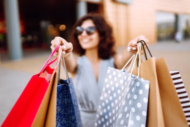Yaz alışverişi. Alışveriş torbalarıyla sokakta yürüyen genç bir kadın. Tüketim, satış, alım-satım, yaşam tarzı kavramı.