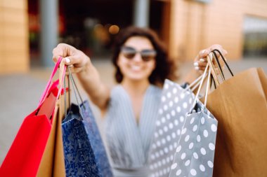 Kadın ellerinde alışveriş torbaları. Şehir caddesinde alışveriş yapan genç bir kadın. Yaz alışverişi. Tüketim, satış, alım-satım, yaşam tarzı kavramı.