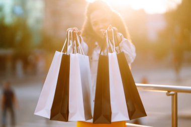Kadın ellerinde alışveriş torbaları. Alışveriş torbalarıyla sokakta yürüyen genç bir kadın. Tüketim, satış, alım-satım, yaşam tarzı kavramı.