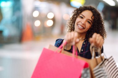Alışveriş torbalarını tutan bir kadının elini yakın çekim. Alışveriş merkezinden sonra genç bir kadın. Tüketim, satış, alım-satım, yaşam tarzı kavramı.