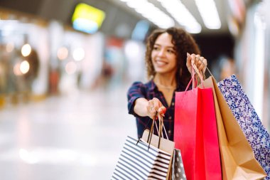 Alışveriş torbalarını tutan bir kadının elini yakın çekim. Alışveriş merkezinden sonra genç bir kadın. Tüketim, satış, alım-satım, yaşam tarzı kavramı.