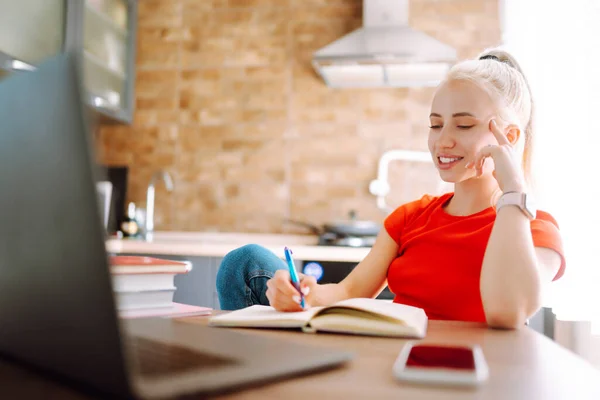 Education and working online. Young female freelancer works and makes notes while working at home in quarantine lockdown.Online shopping in web store.