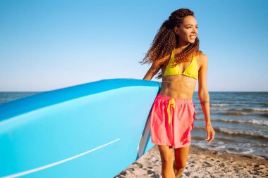 Yaz tatili boyunca sörfçü kadın. Plajda salgı bezleri olan genç bir kadın. Olağanüstü bir spor. Seyahat, hafta sonu, yaşam tarzı..