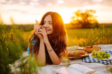 Güzel genç bir kadın parkta piknik yapıyor. Sağlıklı yiyecekler. Taze meyve. İnsanlar, yaşam tarzı, rahatlama ve tatil kavramı.