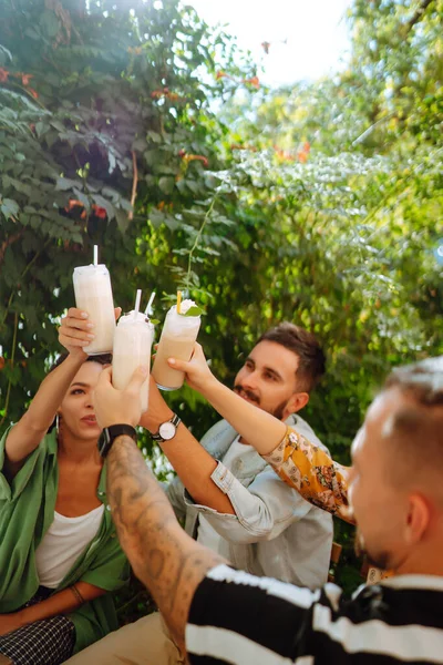 Summer  milkshake. Young friends celebrating summer and drinking milkshakes in a cafe. People, lifestyle, lunch, party, relax concept.