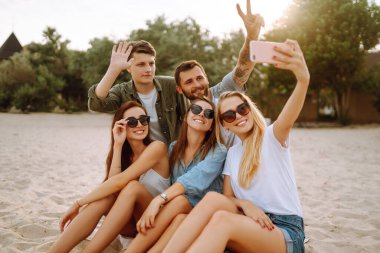 Selfie zamanı. Bir grup arkadaş telefonla selfie çekiyor. Genç arkadaşlar plajda birlikte yaz partisinin tadını çıkarıyorlar. Arkadaşlık ve yaşam tarzı kavramları.