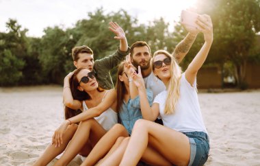 Selfie zamanı. Bir grup arkadaş telefonla selfie çekiyor. Genç arkadaşlar plajda birlikte yaz partisinin tadını çıkarıyorlar. Arkadaşlık ve yaşam tarzı kavramları.