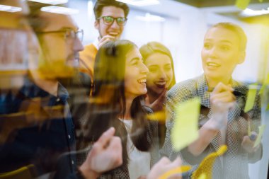 Fikirlerimizi duvar camı ofisindeki kağıt not yazma stratejisiyle paylaşıyoruz. İş adamları ofiste buluşup, fikirlerini paylaşmak için not tutuyorlar. Beyin fırtınası konsepti. Planlama, eğitim, analiz