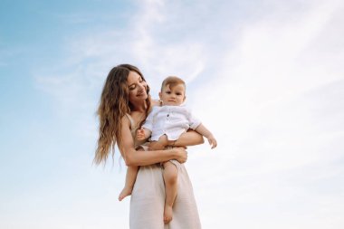 Çocuklu bir anne dışarıda oyun oynarken eğleniyor. Birbirlerini seviyorlar. Küçük oğlu olan genç bir aile kumsalda birlikte vakit geçiriyorlar. Aile, çocukluk, aktif yaşam tarzı konsepti.