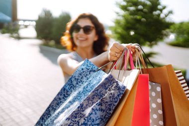 Kadın ellerinde alışveriş torbaları. Alışverişten sonra genç bir kadın. Satış, alışveriş, turizm ve mutlu insanlar konsepti.