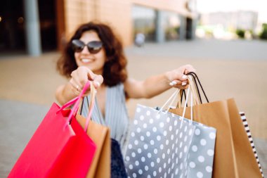 Kadın ellerinde alışveriş torbaları. Alışverişten sonra genç bir kadın. Satış, alışveriş, turizm ve mutlu insanlar konsepti.