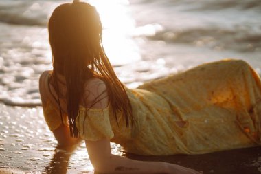 Gün batımında sahilde güzel bir kadın. Seyahat tatili boyunca açık havada huzurlu okyanus doğasının tadını çıkarıyor. Yaz zamanı..