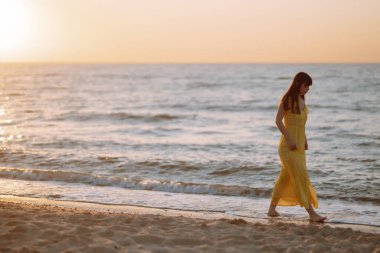 Gün batımında sahilde güzel bir kadın. Seyahat tatili boyunca açık havada huzurlu okyanus doğasının tadını çıkarıyor. Yaz zamanı..