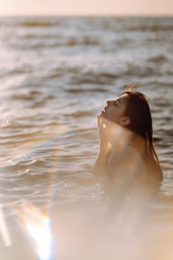 Gün batımında sahilde güzel bir kadın. Seyahat tatili boyunca açık havada huzurlu okyanus doğasının tadını çıkarıyor. Yaz zamanı..