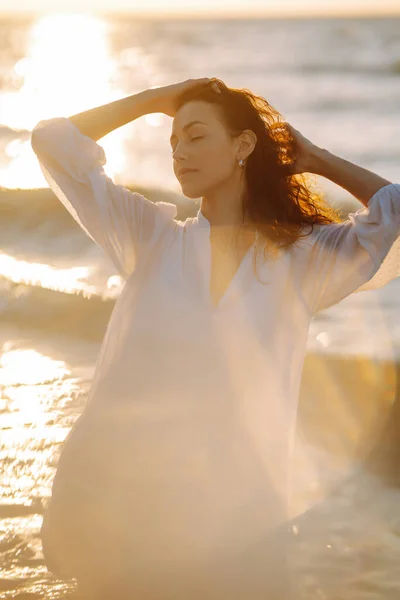 身穿白色飘扬衣服的年轻而快乐的女人沿着海滨散步 女孩看着神奇的日出 夏天的时候旅行 放松和生活方式概念 — 图库照片