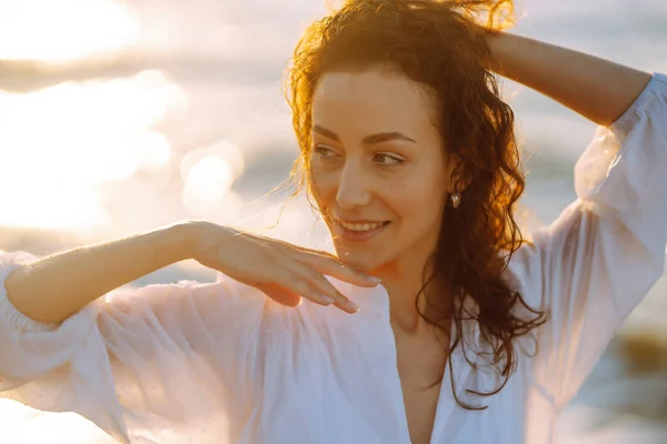 身穿白色飘扬衣服的年轻而快乐的女人沿着海滨散步 女孩看着神奇的日出 夏天的时候旅行 放松和生活方式概念 — 图库照片
