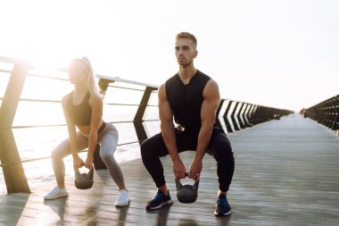 Sağlıklı bir yaşam tarzı. Genç ve güzel bir çift sahildeki iskelede spor egzersizleri yapıyor. Spor, Aktif Yaşam.