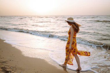 Genç mutlu kadın deniz kıyısında yürüyor. Seyahat, hafta sonu, rahatlama ve yaşam tarzı konsepti.