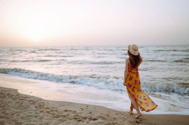 Genç mutlu kadın deniz kıyısında yürüyor. Seyahat, hafta sonu, rahatlama ve yaşam tarzı konsepti.