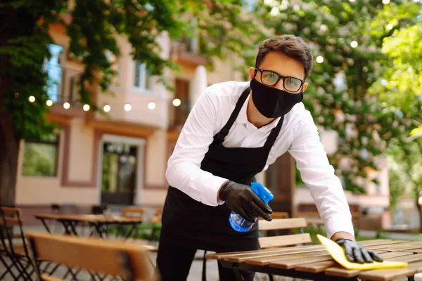 消毒以防止Covid 戴防护面罩和手套的服务员为下一位顾客清洗及消毒餐桌 — 图库照片