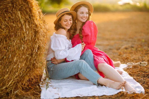 在农村 两名穿着时髦时髦衣服的年轻女子躺在干草袋旁 时尚的概念 放松和生活方式 — 图库照片