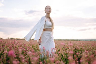 Güzel romantik kız gün batımında dışarıda. Tarlada poz veren şık giyinmiş genç bir kadın. Doğa, tatil, rahatlama ve yaşam tarzı. Moda konsepti.