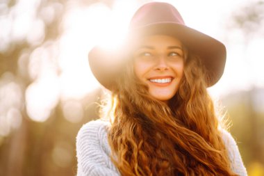 Stylish woman in sweater and hat enjoys autumn nature. People, freedom, lifestyle, travel and vacations concept.