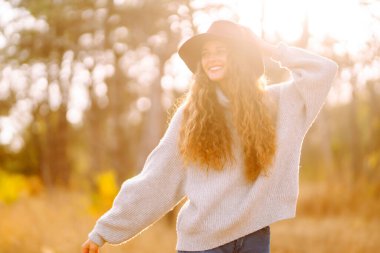 Stylish woman in sweater and hat enjoys autumn nature. People, freedom, lifestyle, travel and vacations concept.