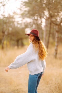 Stylish woman in sweater and hat enjoys autumn nature. People, freedom, lifestyle, travel and vacations concept.