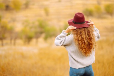 Stylish woman in sweater and hat enjoys autumn nature. People, freedom, lifestyle, travel and vacations concept.